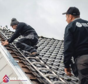 Deux membres de SOS Roof réparant une tuile cassée